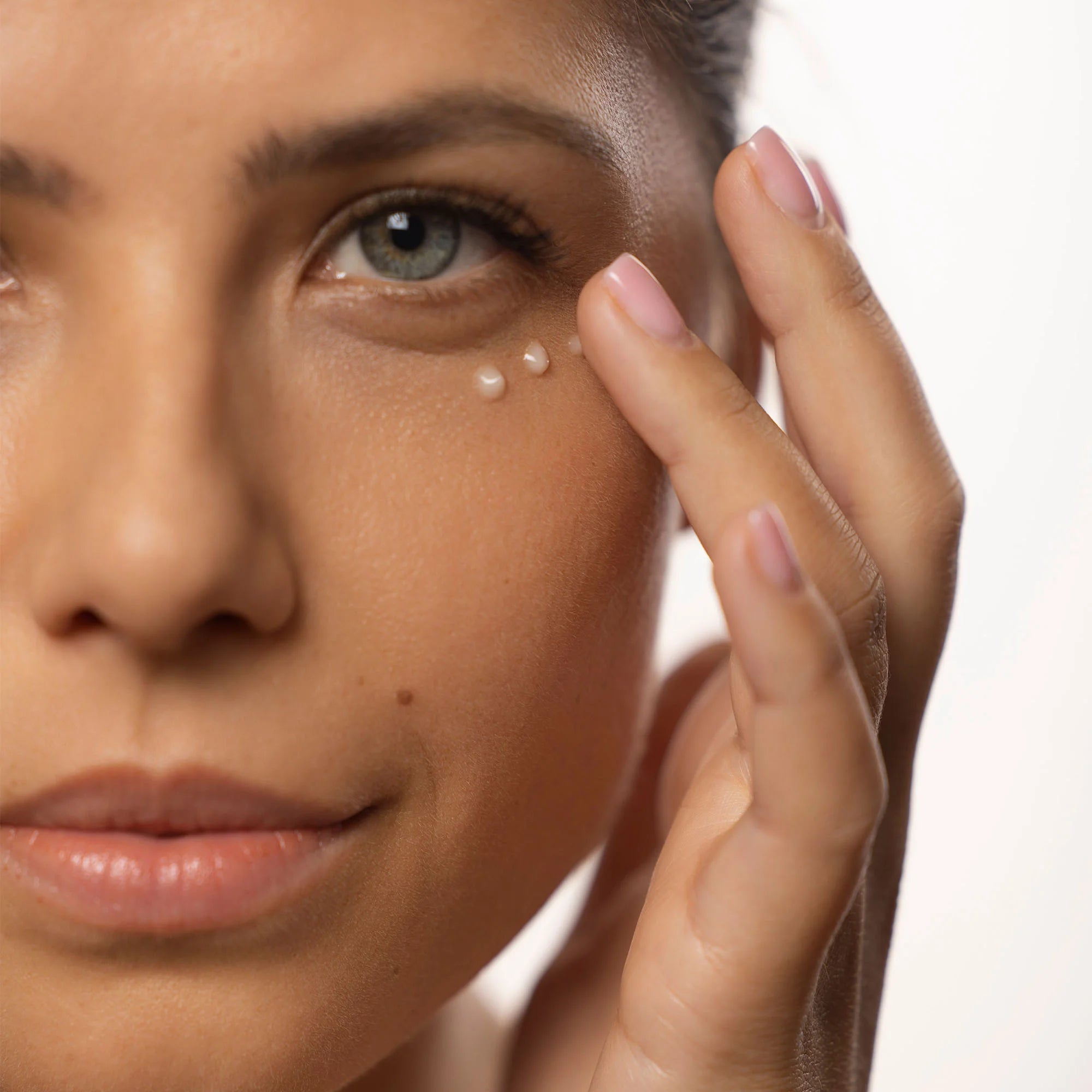 Application du soin contour des yeux anti-poches et cernes sur le visage